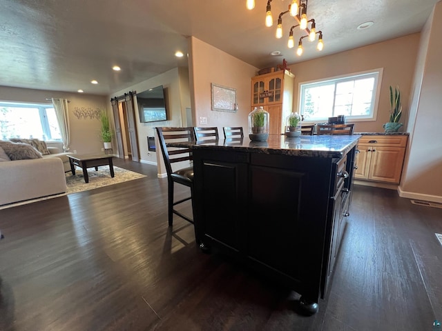 kitchen featuring a kitchen breakfast bar, a kitchen island, open floor plan, and dark wood-type flooring