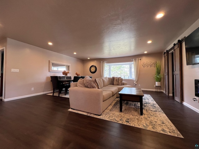 living area featuring recessed lighting, baseboards, dark wood finished floors, and a barn door