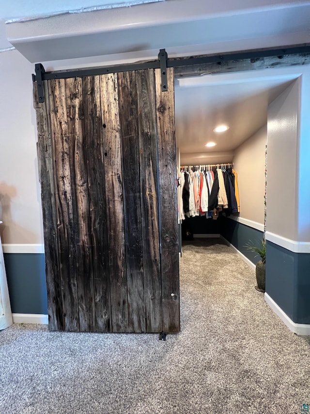spacious closet featuring a barn door and carpet