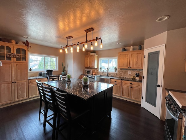 kitchen featuring a kitchen island, range with gas stovetop, backsplash, and dark wood finished floors