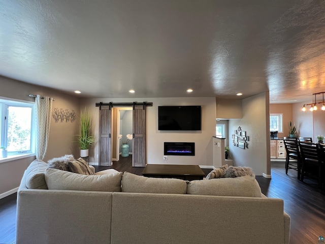 living room with recessed lighting, baseboards, a glass covered fireplace, and dark wood-style floors