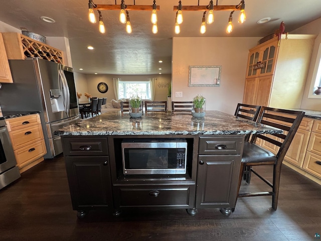kitchen with glass insert cabinets, a breakfast bar area, dark wood-type flooring, dark stone countertops, and stainless steel appliances