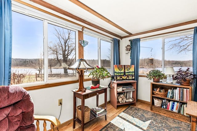 living area featuring baseboards, ornamental molding, a water view, and wood finished floors
