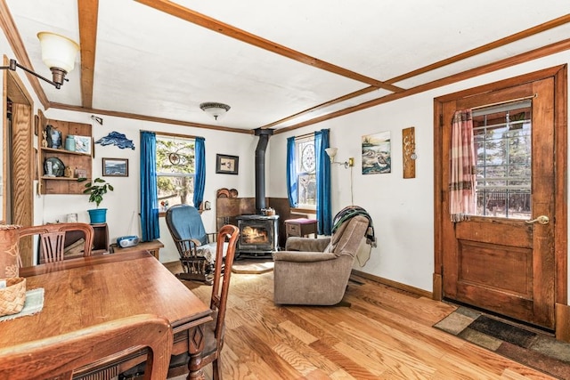 office space with baseboards, ornamental molding, a wood stove, and light wood-style flooring