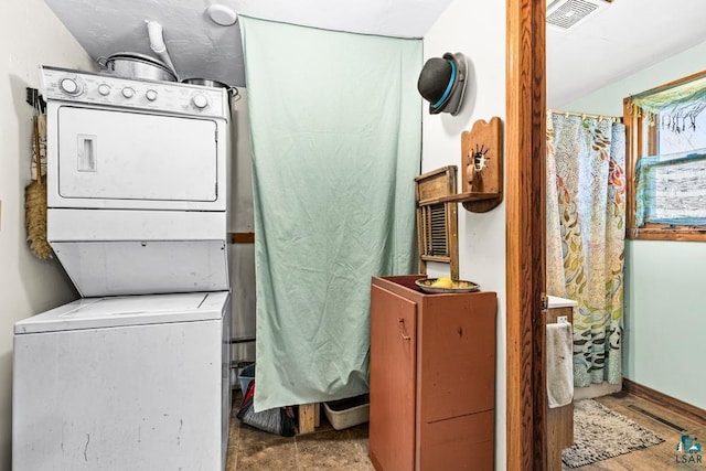 washroom with stacked washer and dryer, laundry area, and visible vents