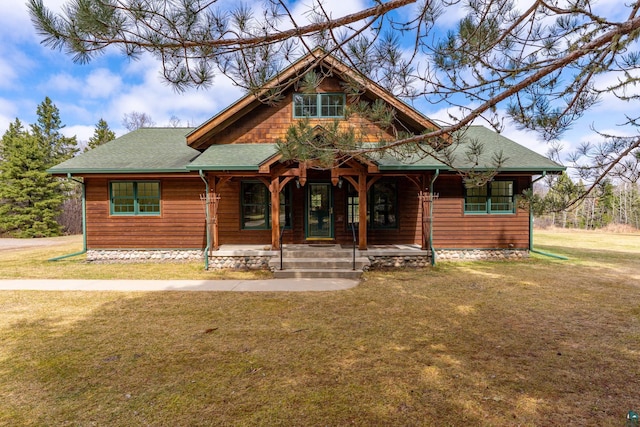 rustic home with a shingled roof, a porch, and a front lawn