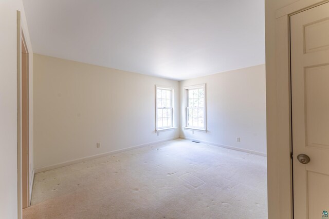 unfurnished room with baseboards and light colored carpet