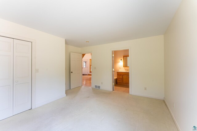 unfurnished bedroom with baseboards, visible vents, light carpet, and a closet