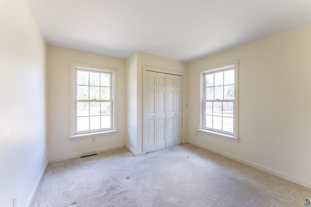 unfurnished bedroom featuring baseboards, carpet, a closet, and visible vents