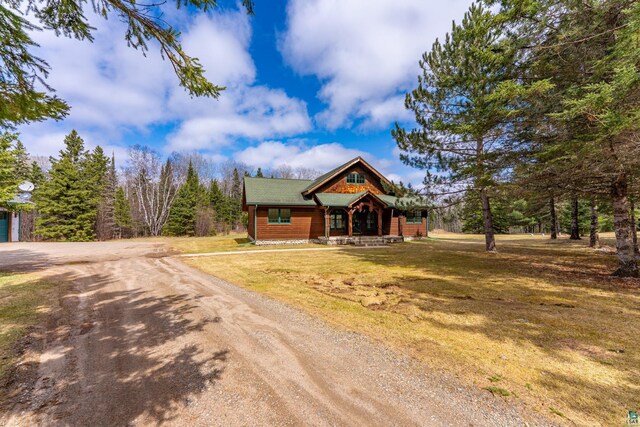 chalet / cabin with dirt driveway, a porch, and a front yard