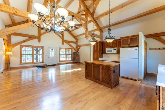 kitchen with a center island, high vaulted ceiling, open floor plan, an inviting chandelier, and white appliances