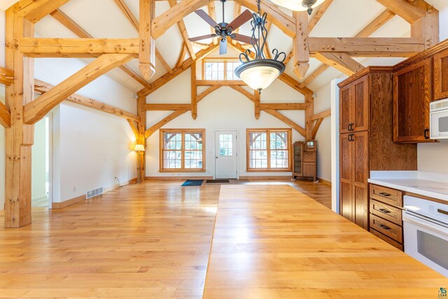 kitchen with a ceiling fan, visible vents, high vaulted ceiling, open floor plan, and white appliances