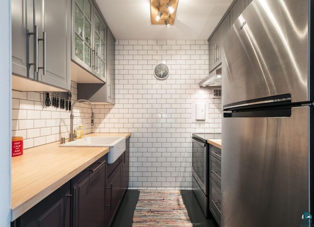 410 Groveland Ave Unit 1203, Minneapolis, MN 55403 - kitchen with a sink, butcher block countertops, stainless steel appliances, tile walls, and glass insert cabinets