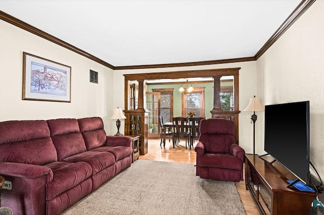 living area with light wood-style floors, crown molding, visible vents, and a notable chandelier