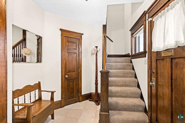 stairs featuring a textured ceiling and baseboards