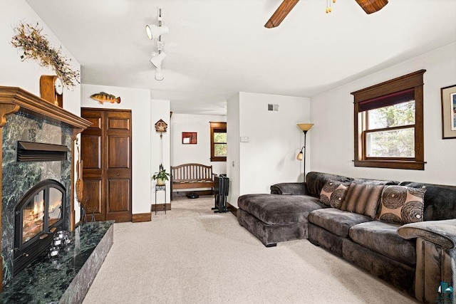 living area featuring ceiling fan, visible vents, baseboards, carpet flooring, and a premium fireplace