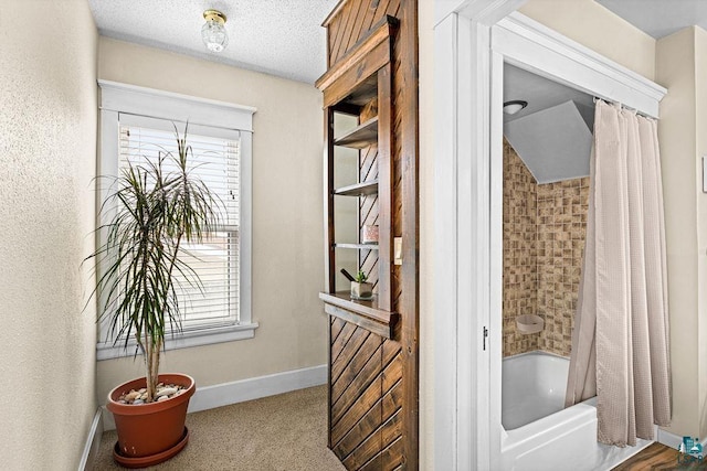 interior space with a textured ceiling, baseboards, plenty of natural light, and shower / tub combo