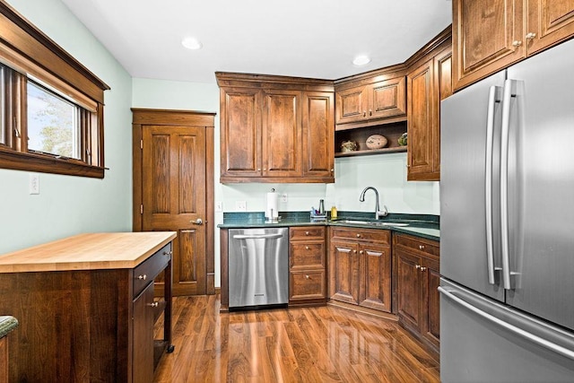 kitchen featuring open shelves, a sink, butcher block countertops, stainless steel appliances, and dark wood-style floors