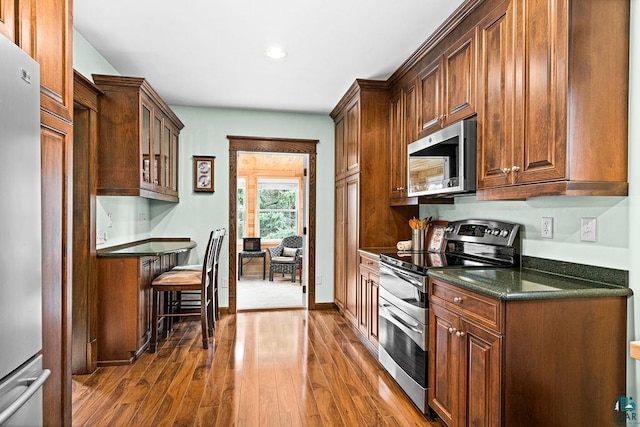 kitchen featuring glass insert cabinets, baseboards, recessed lighting, dark wood finished floors, and appliances with stainless steel finishes