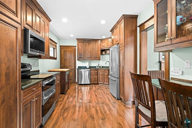 kitchen featuring stainless steel appliances, dark countertops, recessed lighting, and wood finished floors