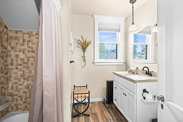 full bath with wood finished floors, shower / tub combo, vanity, baseboards, and radiator heating unit