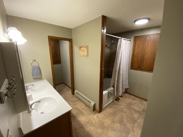 full bath featuring double vanity, a textured ceiling, a sink, and a baseboard radiator
