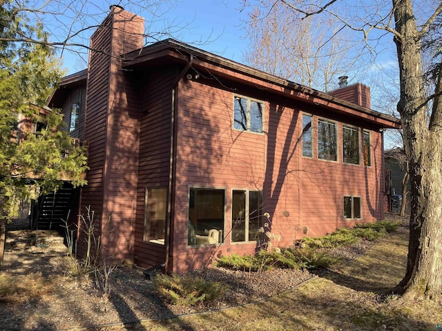 view of side of home with stairs and a chimney