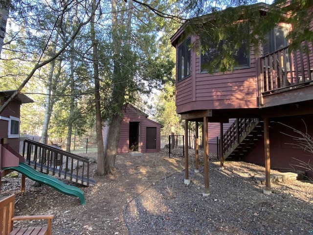 view of side of home featuring stairs, a playground, and an outbuilding