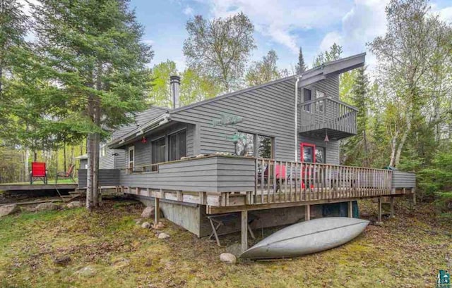 back of house featuring a wooden deck and a balcony