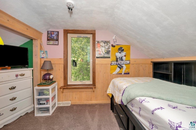 bedroom with wood walls, a textured ceiling, lofted ceiling, and carpet