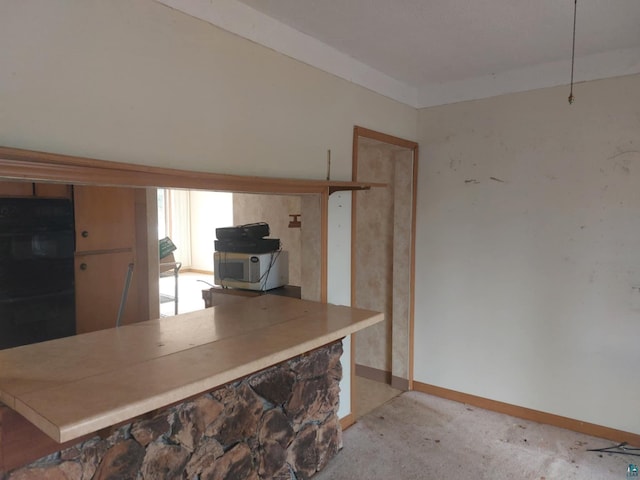 kitchen featuring double oven, baseboards, and light carpet