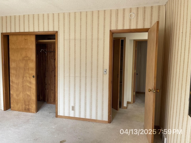 unfurnished bedroom with carpet floors, a closet, wallpapered walls, and a textured ceiling