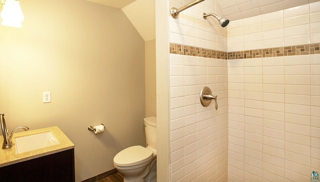 bathroom with vanity, wood finished floors, a tile shower, and toilet