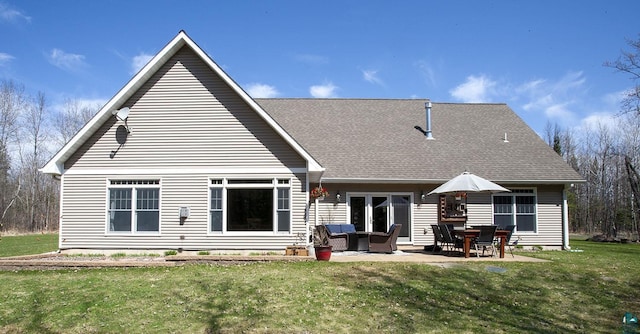 back of house with roof with shingles, a yard, and a patio area