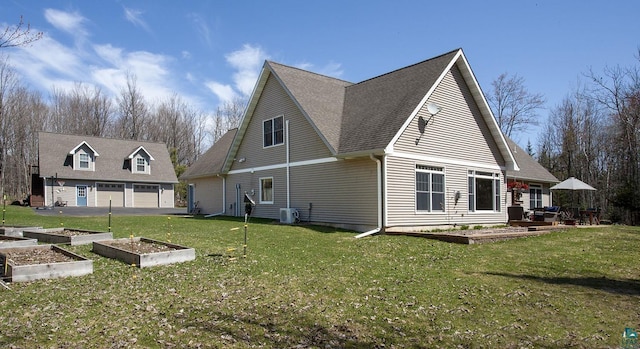 exterior space with a garden, roof with shingles, a lawn, an outbuilding, and a detached garage