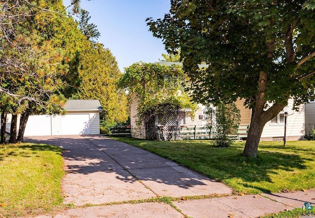 obstructed view of property featuring a detached garage, fence, an outdoor structure, and a front yard