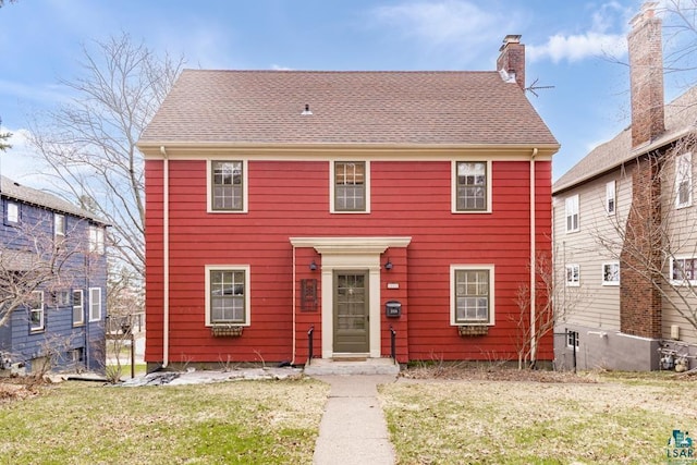 colonial home with a front lawn and a chimney