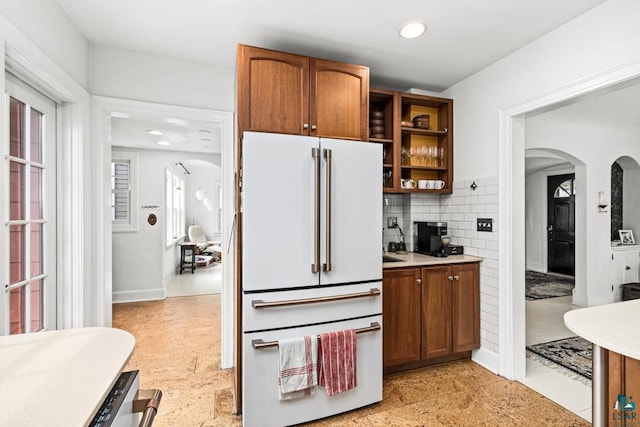 kitchen with freestanding refrigerator, decorative backsplash, recessed lighting, light countertops, and arched walkways