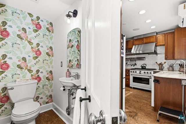 bathroom featuring a sink, toilet, recessed lighting, baseboards, and backsplash