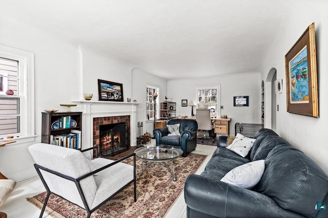 living area featuring a tiled fireplace, arched walkways, and wood finished floors