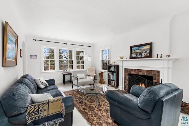 living room with a tiled fireplace, arched walkways, and wood finished floors
