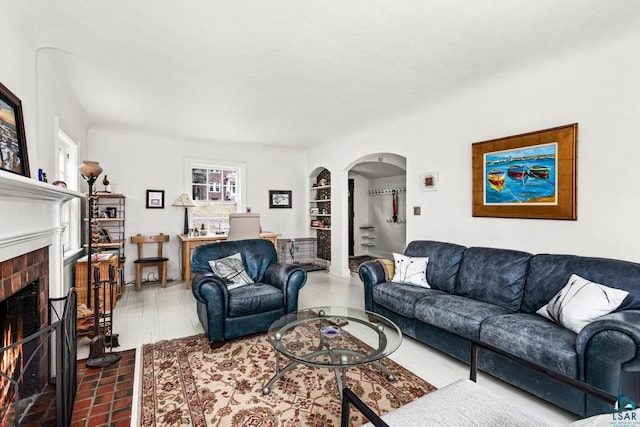 living area featuring arched walkways, built in shelves, and a fireplace