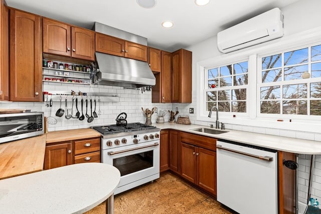 kitchen with tasteful backsplash, a sink, an AC wall unit, under cabinet range hood, and white appliances