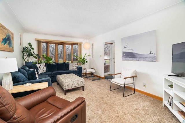 living room featuring carpet floors, arched walkways, and baseboards