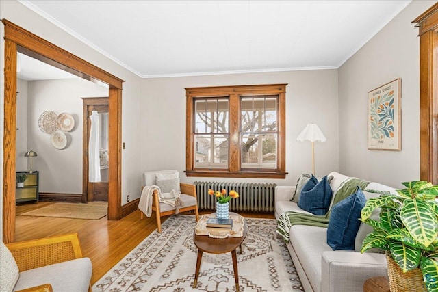 living area with crown molding, baseboards, radiator, and wood finished floors