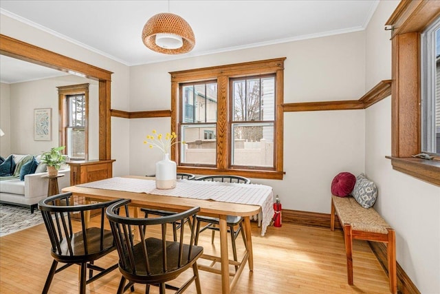 dining room with baseboards, ornamental molding, and light wood finished floors
