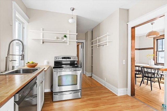 kitchen featuring stainless steel range with electric cooktop, a sink, white cabinets, light wood-style floors, and black dishwasher