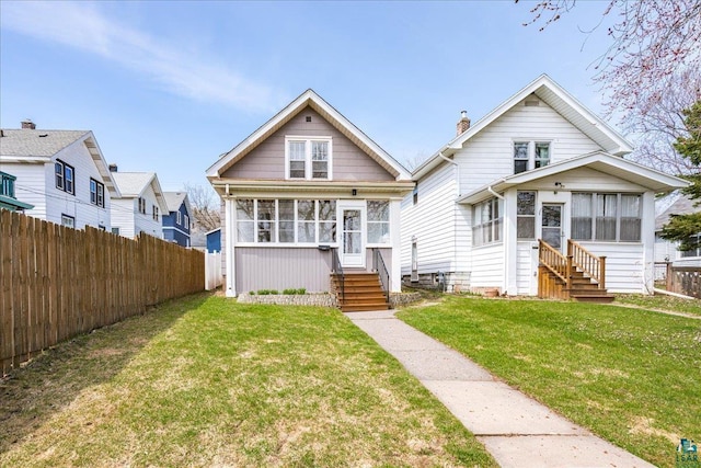 view of front of house featuring a sunroom, a front lawn, fence, and entry steps