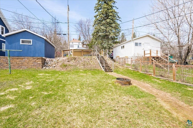 view of yard with fence, stairs, and an outdoor fire pit
