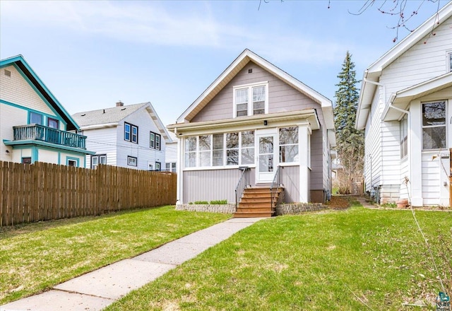 bungalow-style home with fence and a front lawn
